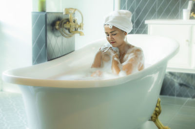 Young woman sitting in bathroom at home