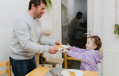 A little girl serves a royal galette to a guy.