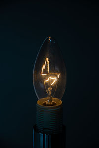 Close-up of illuminated light bulb against black background