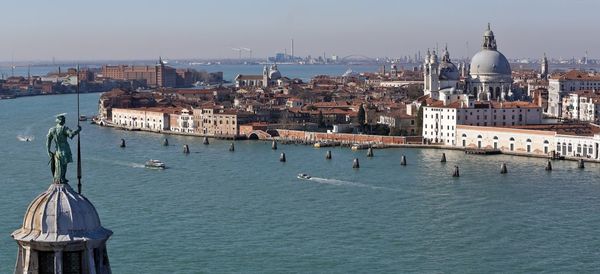 Canal by santa maria della salute in city on sunny day