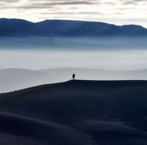 Silhouette men on mountain against sky