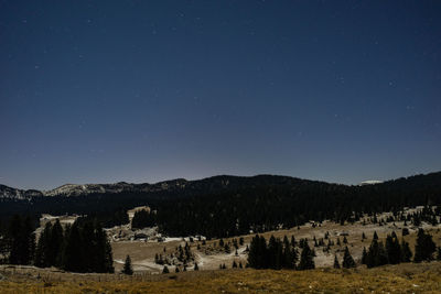 Scenic view of landscape and mountains against star field at night