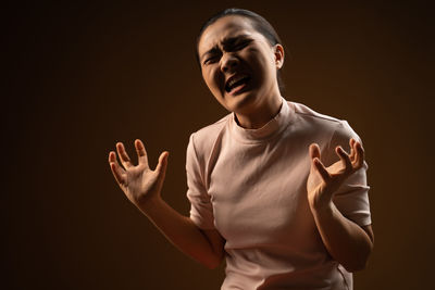 Portrait of young man standing against black background