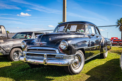 Vintage car on field against blue sky