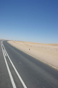 Country road against clear blue sky