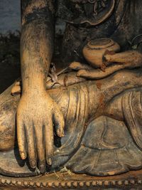 Close-up of old statue against tree trunk