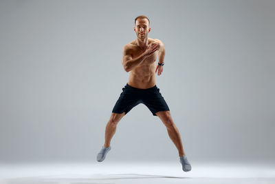 Full length of woman exercising against white background