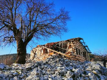 Low angle view of abandoned building against clear blue sky