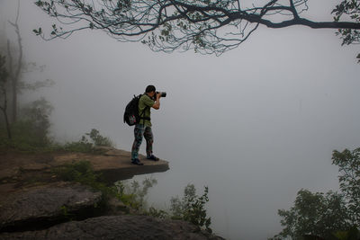 Man standing on rock against sky