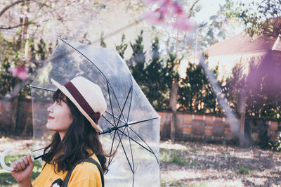 Side view of woman looking away against trees