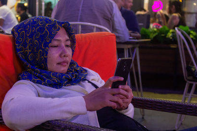 Midsection of man using mobile phone while sitting on chair