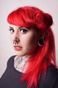 Portrait of young woman with redhead standing against wall