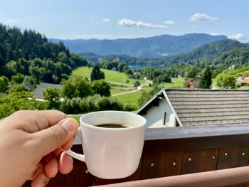 Woman holding coffee cup against mountains