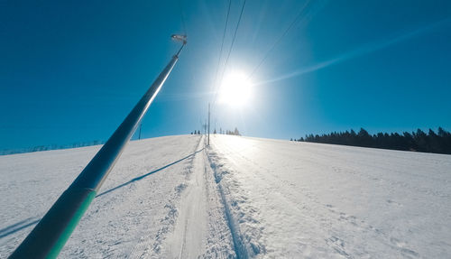 Snow covered land against clear blue sky