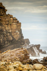 Rock formation on beach against sky