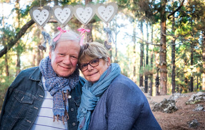 Portrait of senior couple in warm clothing standing against trees
