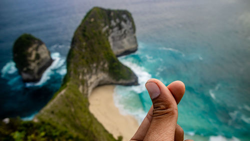 Person hand on rock by sea