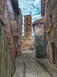 Narrow footpath leading towards castle against sky