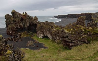 Scenic view of cliff by sea against sky