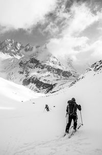 Rear view of people skiing on snowcapped mountain against sky