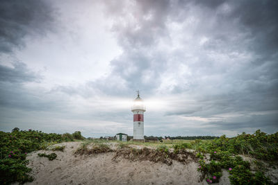 Lighthouse amidst buildings against sky