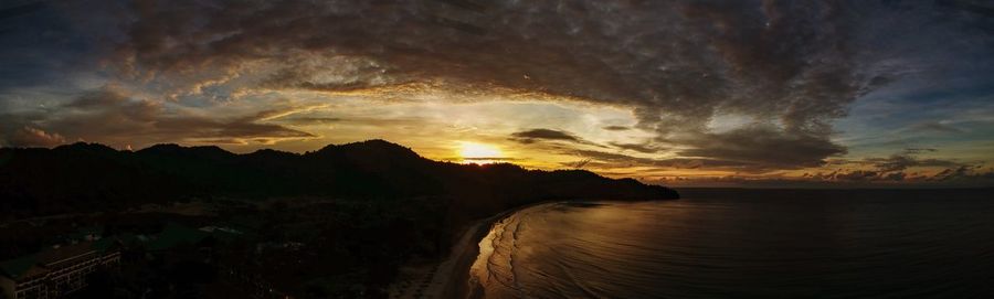 Scenic view of sea against dramatic sky during sunset