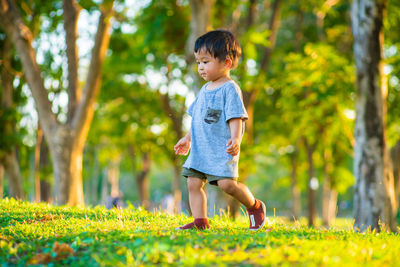 Full length of boy on grass against trees