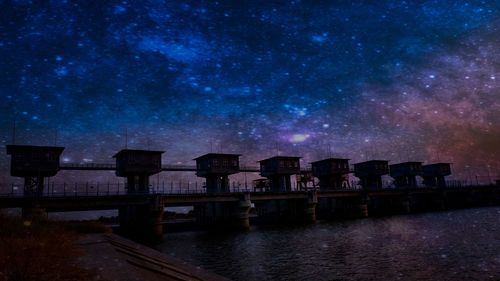 Scenic view of lake against buildings at night