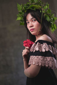 Portrait of beautiful young woman standing by flowering plant