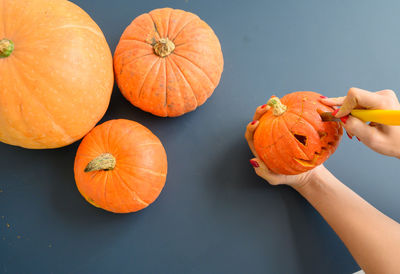 Close-up of hand holding pumpkin against orange background