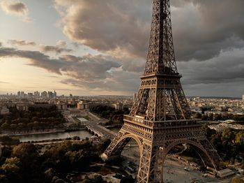 Communications tower in city against cloudy sky