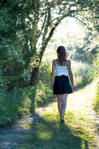 Full length rear view of woman walking on footpath