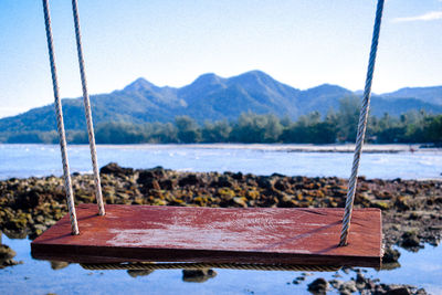 Swing on lake against clear sky