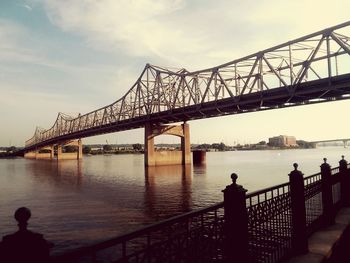 Bridge over calm river against sky