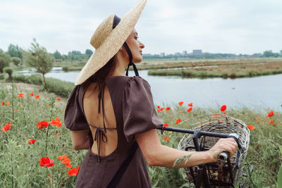 Rear view of woman with bicycle standing by lake