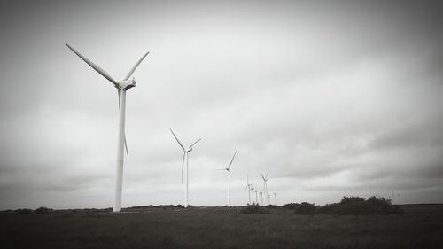 Windmills on field against sky