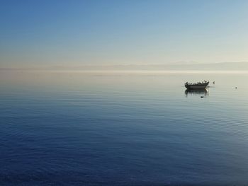 Boat sailing in sea against sky during sunset