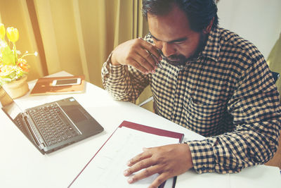 Midsection of man using smart phone while sitting on table