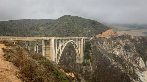 Arch bridge over mountains against sky