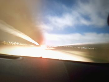 Close-up of illuminated bright sun against sky during sunset