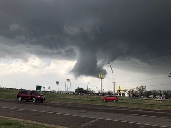 Cars on road against cloudy sky