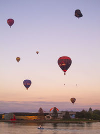 Hot air balloons flying against sky during sunset