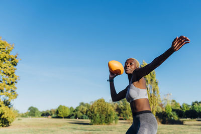 Young sportswoman throwing american football in field