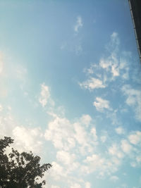 Low angle view of trees against cloudy sky