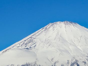 Low angle view of snowcapped mountain against clear blue sky