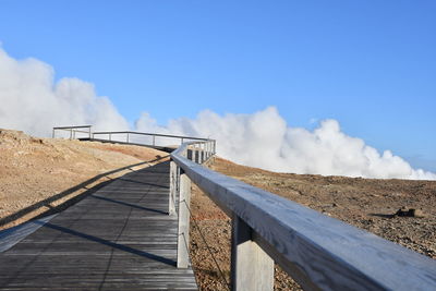 Low angle view of railing against blue sky