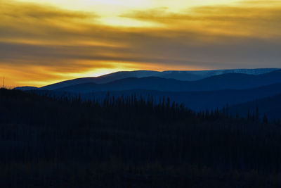 Scenic view of silhouette mountains against orange sky