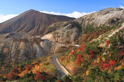 Scenic view of road by mountains against sky during autumn