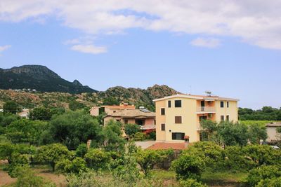 Houses by trees and mountains against sky