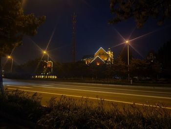 Illuminated light trails on road against sky at night